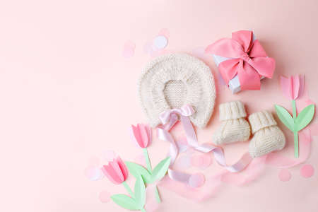 Beautiful composition with baby booties shoes, bonnet and gift box on pink background. Concept of baby shower party, pregnancy, mother day, first birthday holiday card, copy space, bannerの写真素材