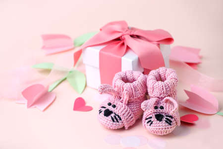Pair of small funny baby socks with gift box, decorative flowers on pink background with copy space for your warm message, baby shower, first newborn party background, copy spaceの写真素材