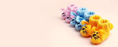 Pregnancy motherhood perenthood concept, Three pairs of baby booties on pastel background, baby shower, first birthday party banner, handmade socks, daycare, kindergarten, nursery, mother momの写真素材