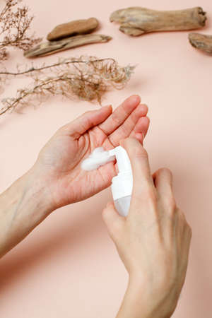 Woman hand take some cleaner foam from Pure white plastic of cleaner foam on trendy beige earth tones neutral background. Hygiene, skincare, healthcare concept, copy spaceの写真素材