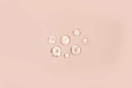 Lotion transparent gel drops texture background, Close-up drops transparent cosmetic aloe vera gel on neutral beige background with copy space. Body care and skin care, moistirize, abstractの写真素材