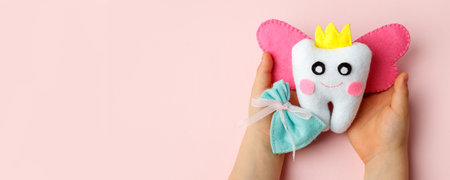 Little child holding felt tooth fairy toy in his hands on pink background. Easy and funny kids...