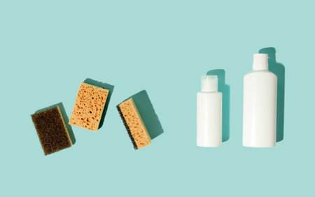 Set of neutral beige clean sponges, bottles with liquid soap or disinfect on blue background. Banner...