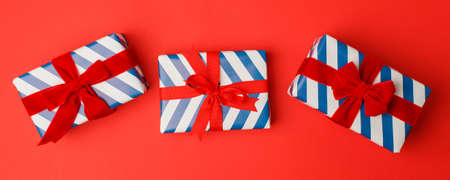 4th of July American Independence Day. Happy Independence Day. White blue stripe gift boxes with red bow on red background. Flat lay, top view, copy space, banner, copy space, sale, Christmasの写真素材