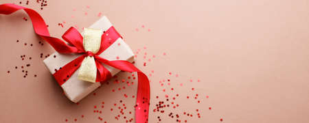 Red Beige theme craft gift box present gift with bright red ribbon and confetti star shape, holiday, xmas, christmas 2022. shopping, sale banner, flyer, coupon concept, copy spaceの写真素材