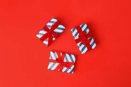 Blue and white stripe gift boxes with red bows on classic red background in the national colors of...