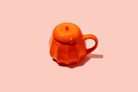 Ceramic Coffee tea soup cup as pumpkin on pink. Halloween concept, hard shadow, minimalの写真素材