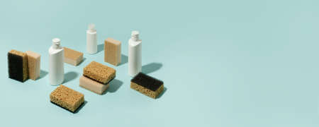 Set of neutral beige clean sponges, bottles with liquid soap or disinfect on blue background. Banner for site, concept for laundry, cleaning service, advertising, spring regular cleaning dayの写真素材