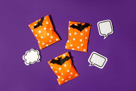 Halloween holiday concept with party gift paper bag decor and candy corn on bright violet purple backgtound, copy space, invitation, flyer, hard shadow, trendy conceptの写真素材