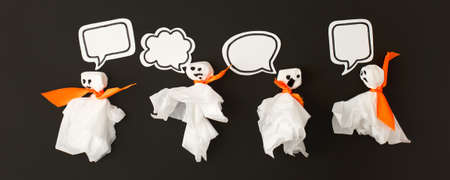 Halloween party concept - ghosts from paper napkin with speaking bubbles for text on black...