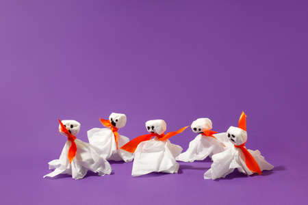 Halloween paper decorations on bright purple violet background. Black ghosts from paper napkins. Halloween concept. Flat lay, top view, overhead. Party greeting card, invitation, flyer, bannerの写真素材