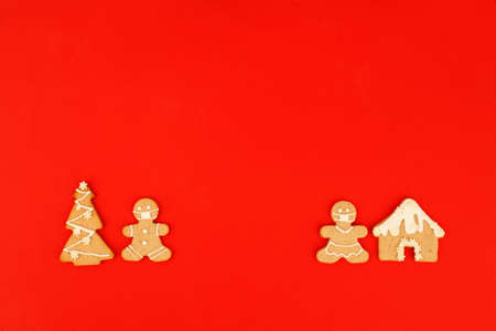 Happy New Year's 2022  set of gingerbread man in face mask from ginger biscuits glazed sugar icing decoration on classic traditional red background, minimal seasonal pandemic winter holiday bannerの写真素材