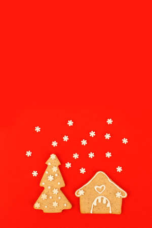 Happy New Year's Christmas card - traditional tree and house from ginger biscuits on red background, minimal stylish seasonal winter holiday card, banner, flyer, coupon invitation, stay home conceptの写真素材