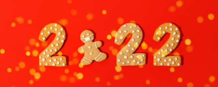 Happy New Year's, Christmas set of numbers 2022, gingerbread man in face mask from ginger biscuits glazed sugar icing decoration on red background, seasonal pandemic winter holiday bannerの写真素材