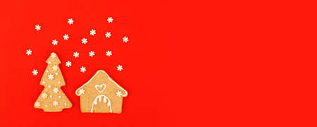 Happy New Year's Christmas card - traditional tree and house from ginger biscuits on red background, minimal stylish seasonal winter holiday card, banner, flyer, coupon invitation, stay home conceptの写真素材