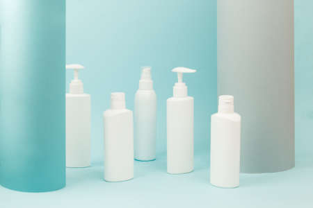 Set of white cosmetic bottles with soft shadows on light blue background. Home and beauty salon care...