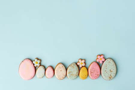 Sweets, pastry, gingerbread cookies for Easter table. Easter and tender simple flowers on blue background top view copy space, spring seasonal holiday banner for your sute, flyer, couponの写真素材