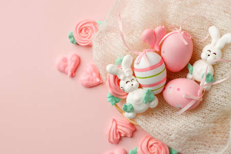 Pastel colored Easter eggs in nest, sweet tender decor from funny meringue and on pink background....