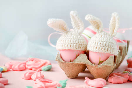 Happy Easter holiday concept with cute handmade eggs, knitted bunny hats and sweet pink decor, copy...