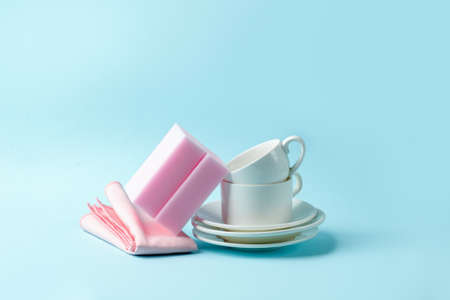 Set of pink sponges and white cups on blue background, kitchenware, house cleaning service concept, copy space, banner, flyer, mockup, minimal designの写真素材