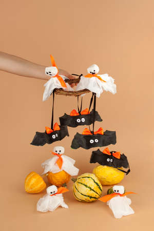 Paper toy ghost, bat decoration for Halloween party in kids hand. Easy crafts for kids on beige...