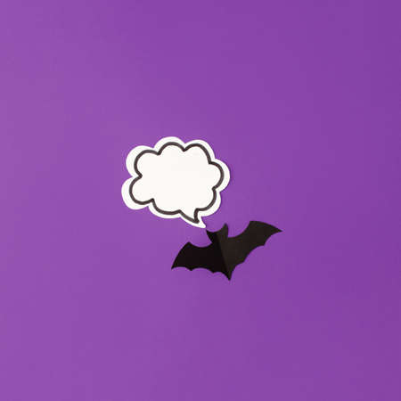 Halloween bats decorations and chat bubble mock up on purple background. Flat lay, top view, minimal...