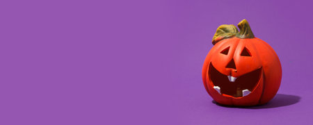Jack-o-lantern, pumpkin toy for Halloween on purple background. Plastic pumpkin, trick or treat, seasonal celebration. Traditional autumn holiday decor, Copy space, bannerの写真素材