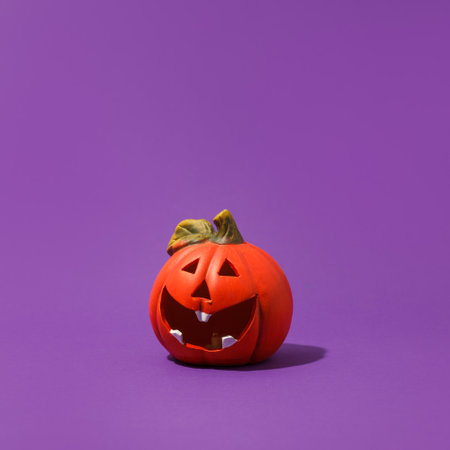 Jack-o-lantern, pumpkin toy for Halloween on purple background. Plastic pumpkin, trick or treat, seasonal celebration. Traditional autumn holiday decor, Copy space, bannerの写真素材