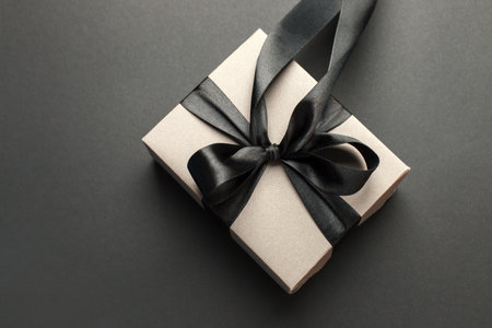 Craft gift box on a dark background, decorated with a textured bow, creating a romantic luxury...