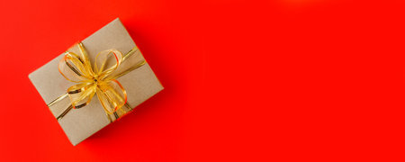 Craft gift box on red background, decorated with a textured bow, creating a romantic luxury atmosphere. For birthday, anniversary gifts, gift post cards, banner, flyer, invitation, voucherの写真素材