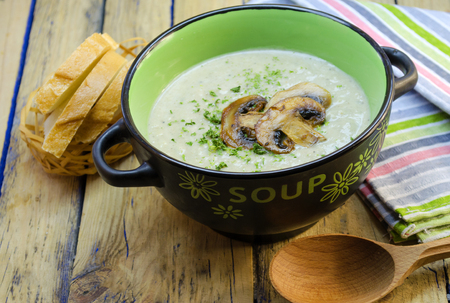 mushroom cream soup in a tureen on a wooden tableの写真素材