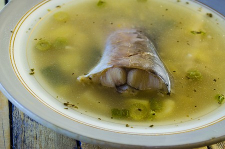 cooked fish soup on the plate closeup with fishの写真素材