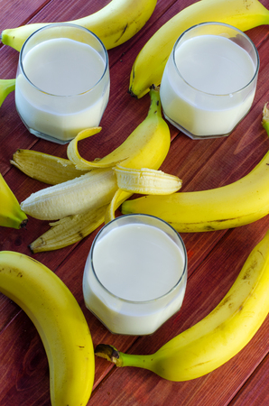 banana and milk in a glass on a wooden backgroundの写真素材