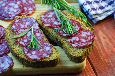 sausage sandwiches on a wooden board and spices closeupの写真素材