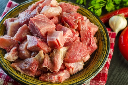 Raw meat chopped into pieces on a plate prepared for further cookingの写真素材