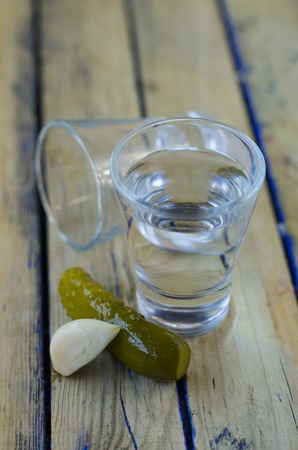 Vodka and pickled cucumber closeup on a wooden tableの写真素材