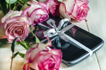 digital tablet with festive ribbon and roses on a white backgroundの写真素材