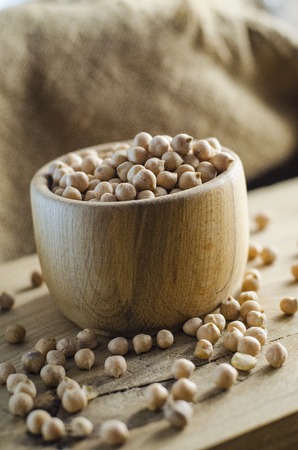 raw chickpeas in a bowl on a wooden boardの写真素材