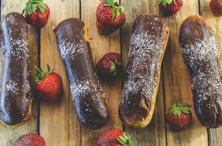 Chocolate profiteroles and fresh strawberries on a wooden tableの写真素材