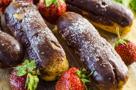 Chocolate profiteroles and fresh strawberries on a wooden tableの写真素材
