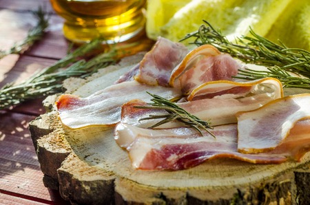 strips of fresh bacon and spices on a wooden boardの写真素材