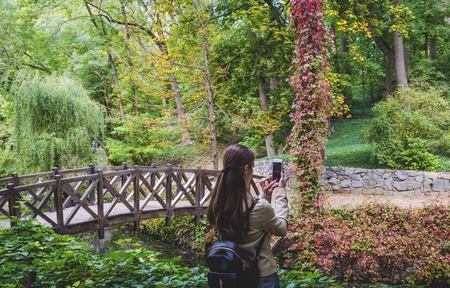 girl takes on the phone a beautiful landscape in the parkの写真素材