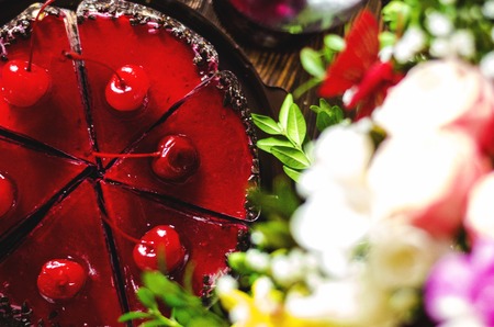 birthday cake with cherry on a background of flowersの写真素材