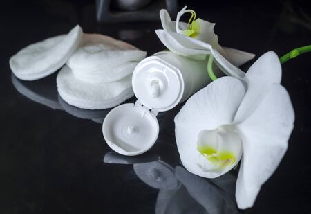 Herbal dermatological cosmetic hygienic cream with flowers for skin care in a tube on a black backgroundの写真素材