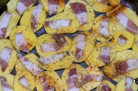 raw sliced potatoes with bacon and spicesの写真素材