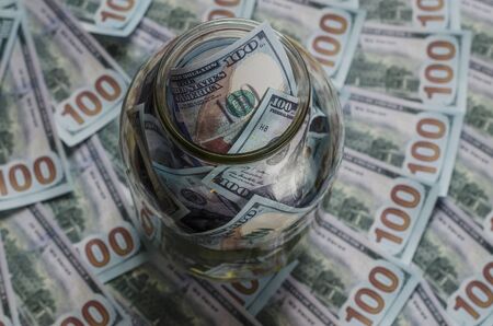 One hundred dollar bills in a glass jar as in a piggy bank for savingの写真素材