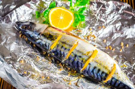 Raw mackerel with lemon and spices on foil, prepared for bakingの写真素材
