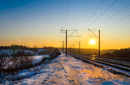 Footsteps in the snow along the railway tracks in winter at sunset