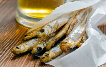 Smoked, salted fish for beer on paper with a glass of beerの写真素材