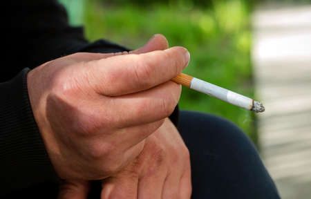 Man with cigarette in hand, smoker close up.の写真素材